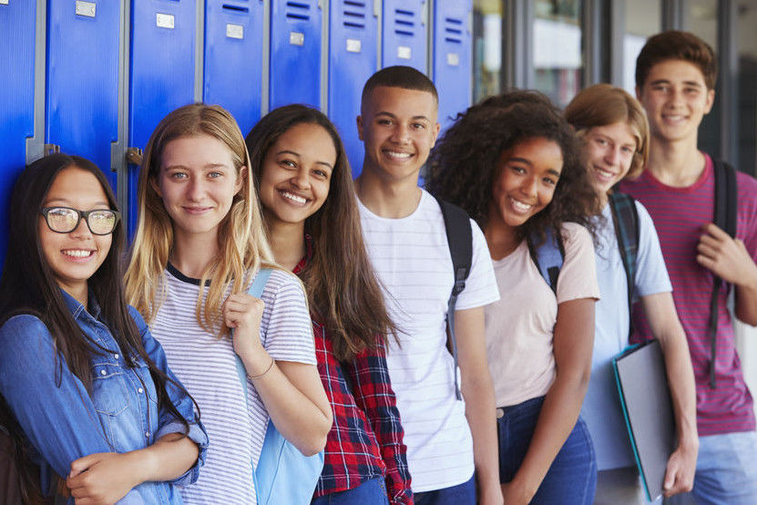 Teenage school kids smiling to camera in school corridor